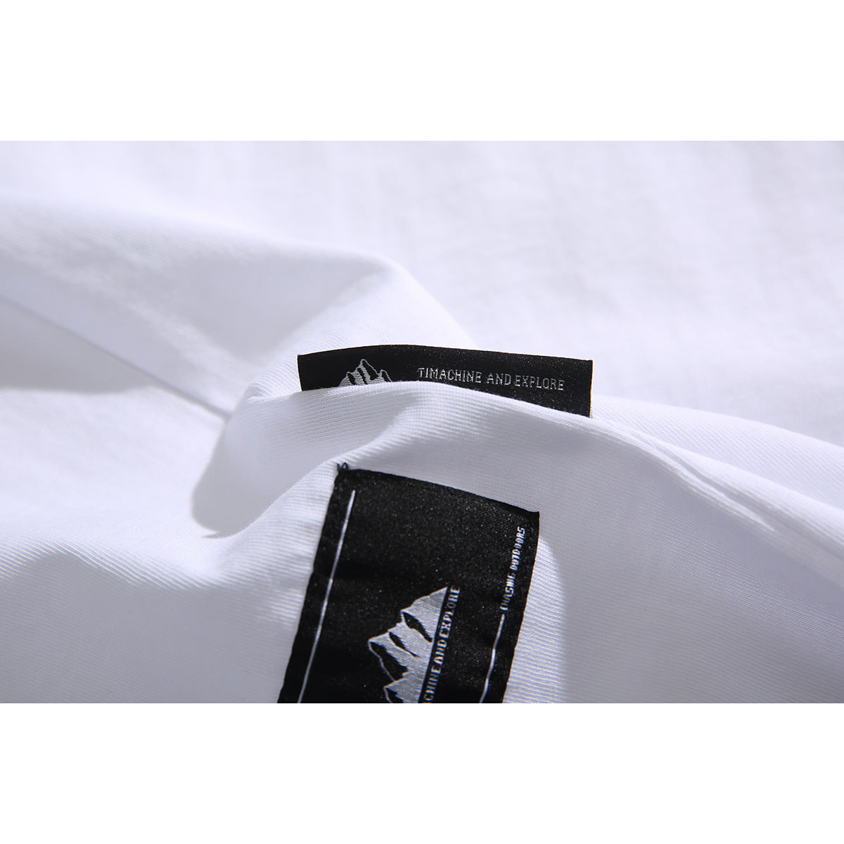 Close-up of a white T-shirt showing black woven brand labels at the neckline.