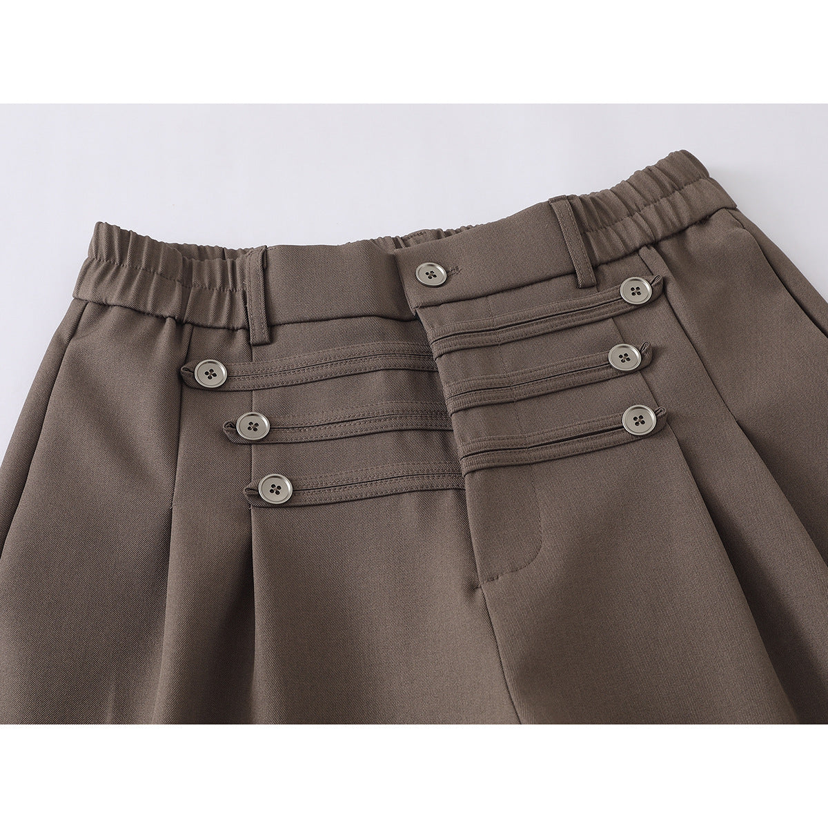 Close-up of taupe wide-leg trousers showing the elasticized waistband, belt loops, button closure, and decorative front