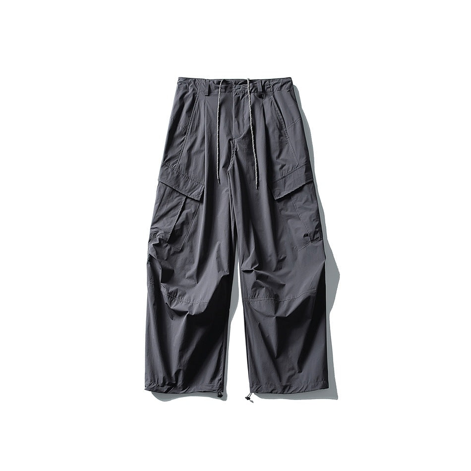 Dark gray wide-leg cargo pants flat lay with drawstring waist, large flap pockets and drawstring hems