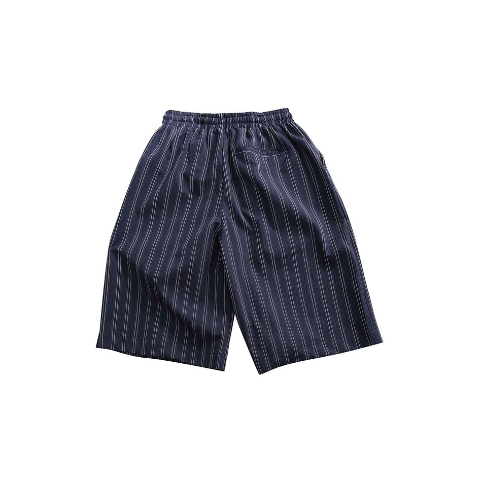 Back view of loose navy pinstriped shorts with an elastic waistband and a patch pocket, laid flat on white.