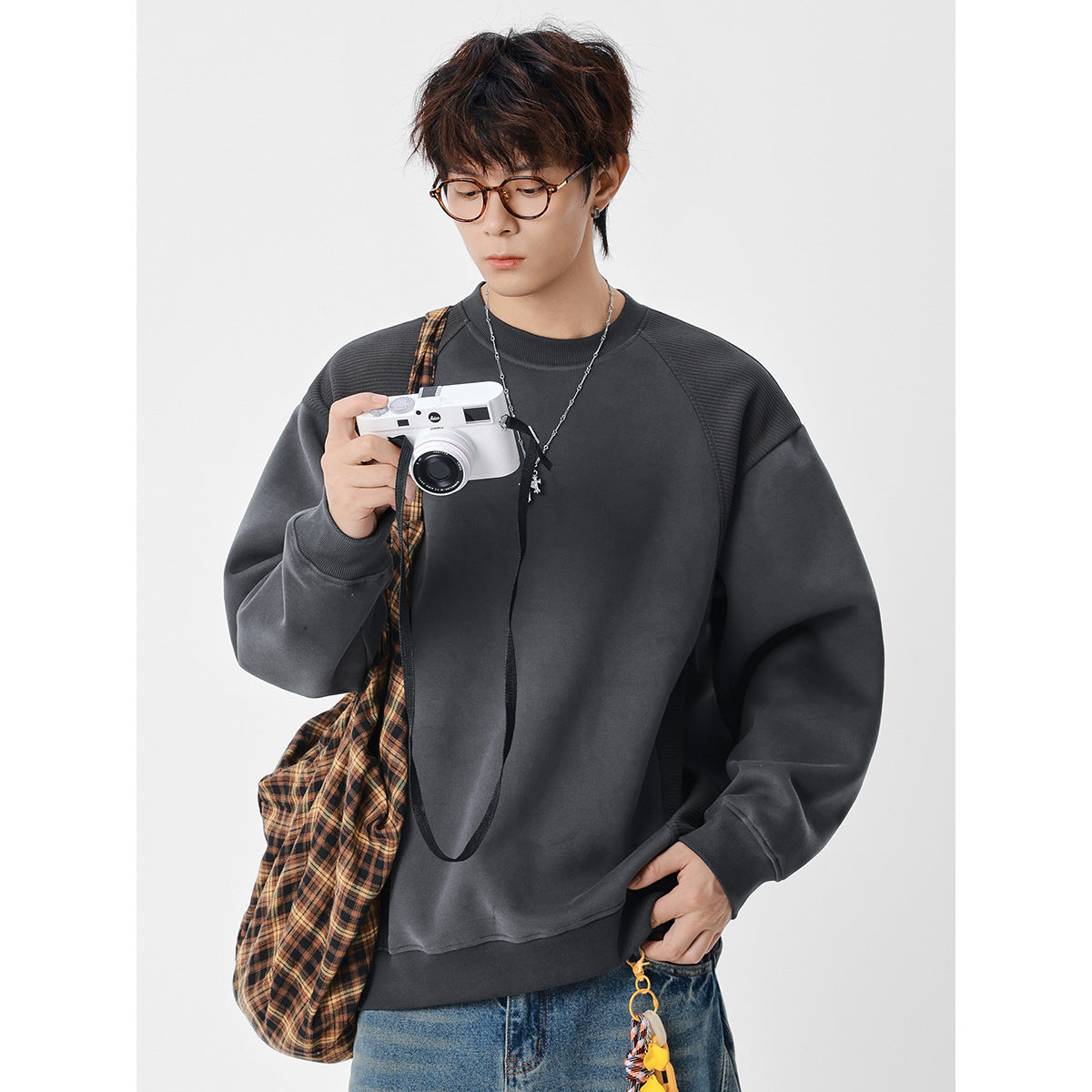 Model wearing an oversized charcoal gray crewneck sweatshirt with textured shoulder panels.