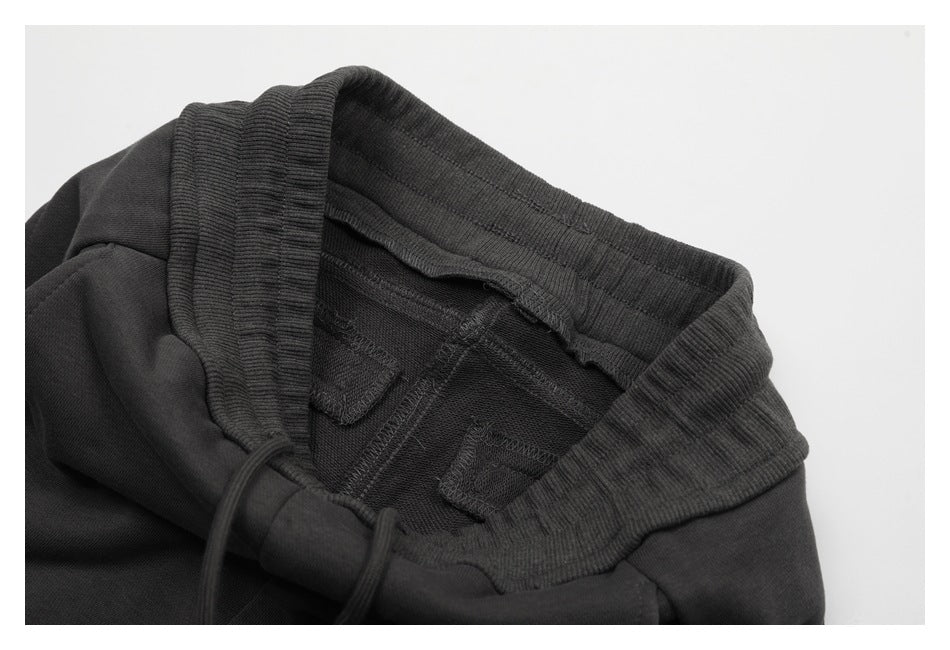 Close-up of a black garment's ribbed elastic waistband, inner stitching, and drawstring.