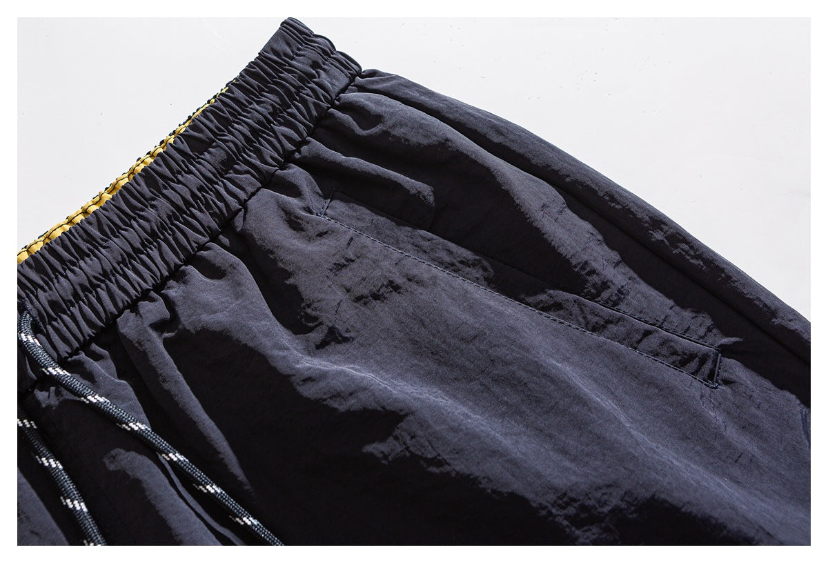 Close-up of dark shorts showing the elastic waistband and angled front pocket.