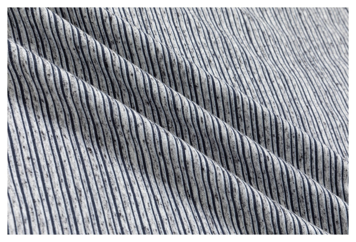 Close-up of gray fabric with narrow navy stripes and subtle speckling, shown in soft folds.