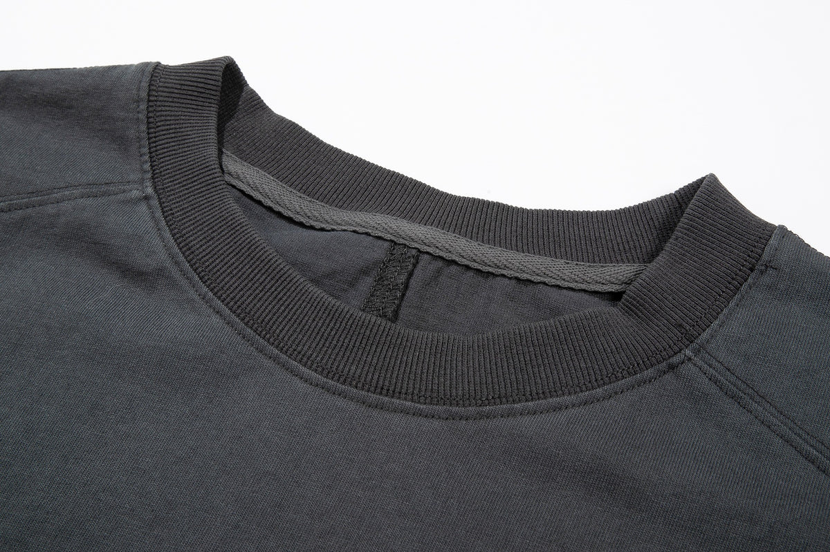 Close-up of the charcoal top's ribbed crew neck, inner binding and shoulder stitching.