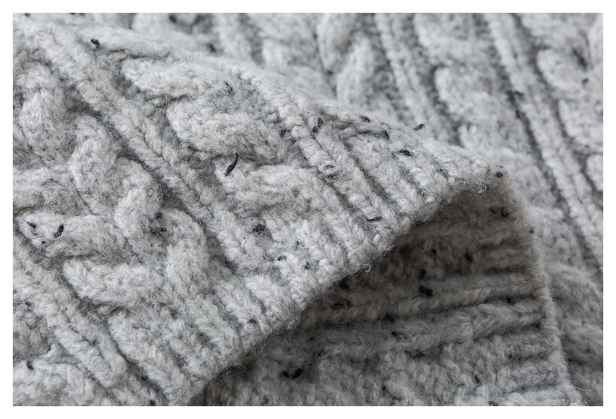 Close-up of a folded edge in chunky light gray flecked knit, showing the raised stitching and texture.