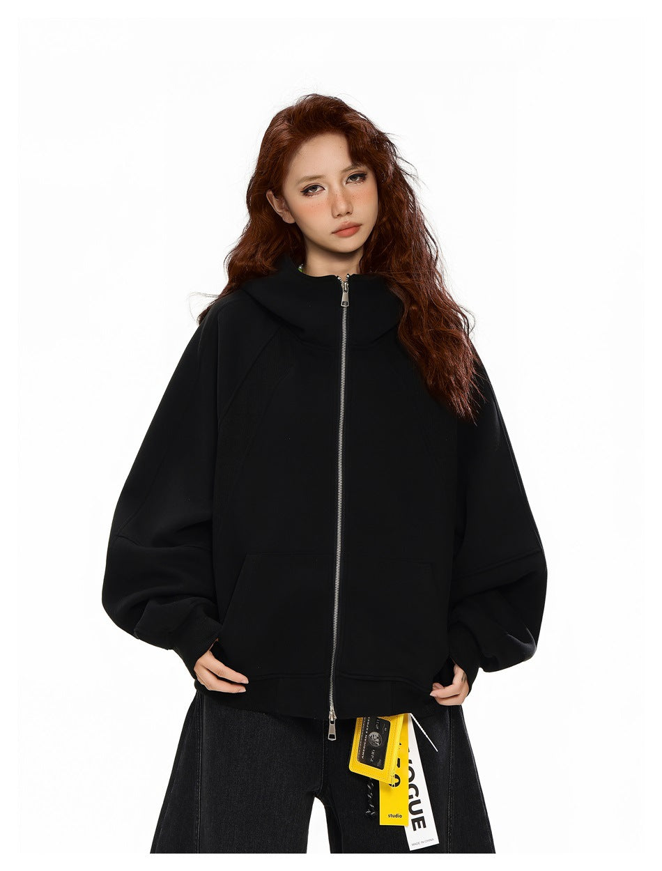Model wearing a black oversized zip hoodie zipped to the neck, with roomy sleeves and front pockets.