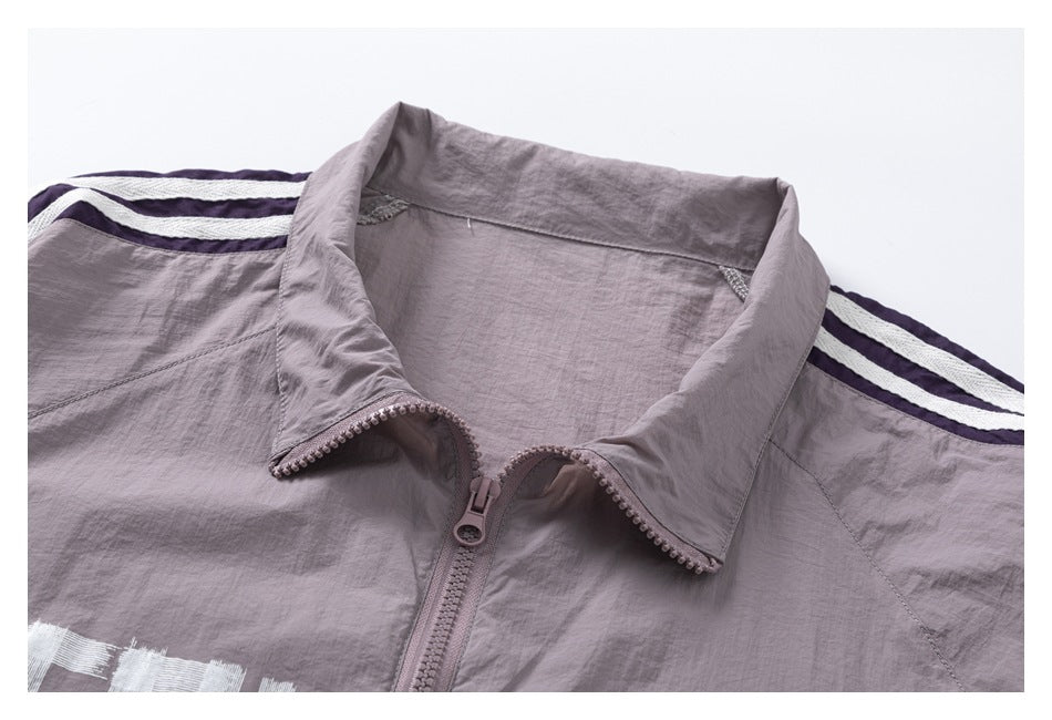 Close-up of a mauve zip-up jacket collar and shoulder with purple and white stripes.