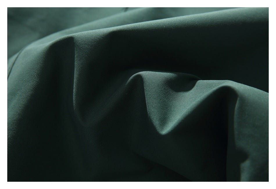 Close-up of dark green fabric draped in soft folds, showing its fine surface texture.
