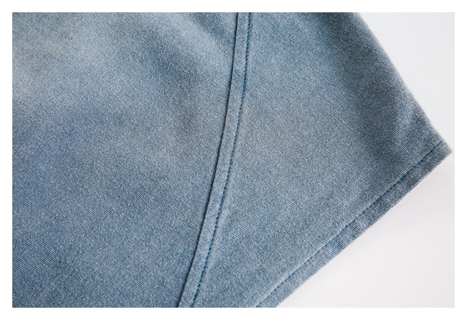 Close-up of blue-gray knit fabric with a curved seam and stitched hem.