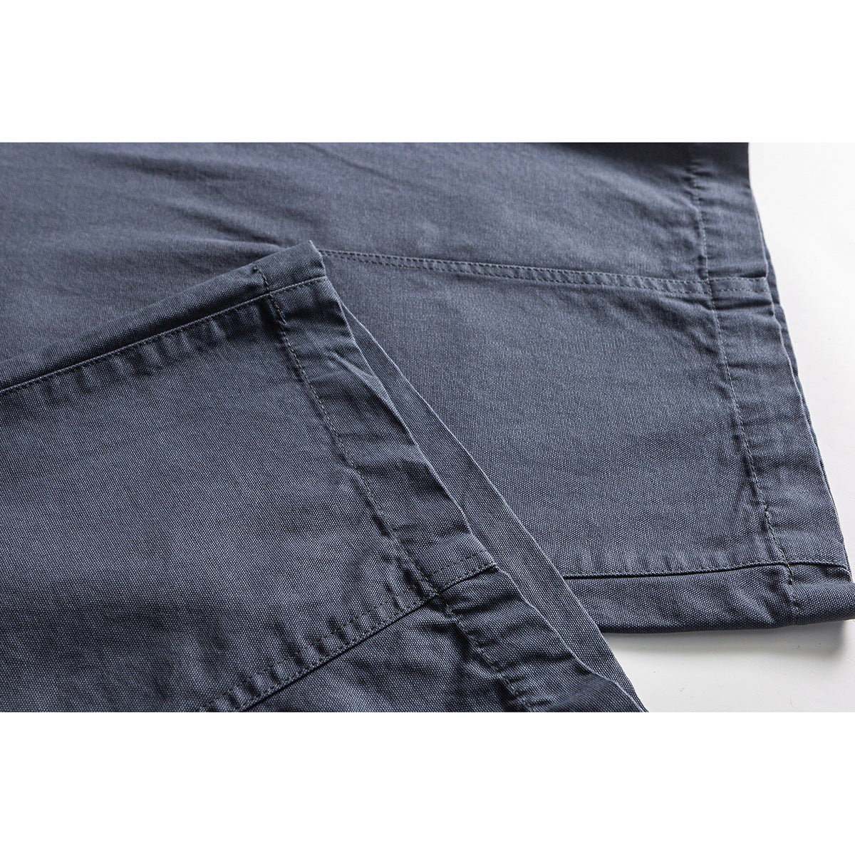 Close-up of slate-blue pants showing stitched seams and a folded hem.