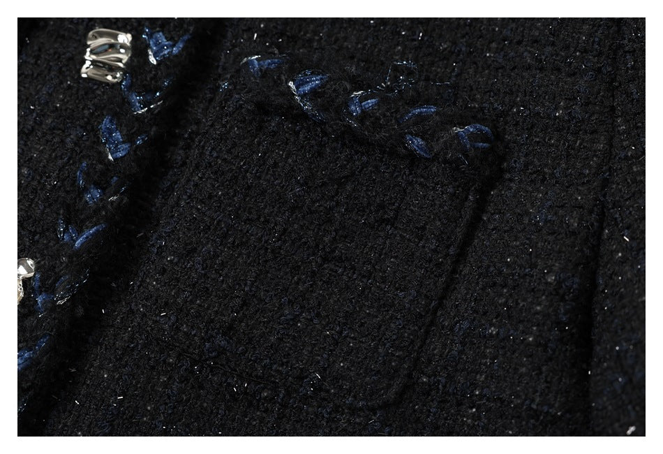 Close-up of a black jacket pocket with blue embroidered trim and a silver-tone decorative fastener.