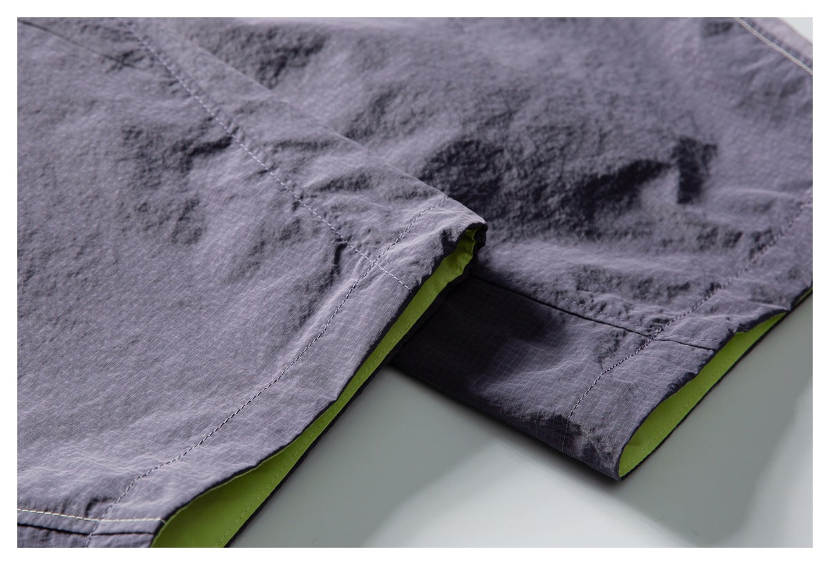 Close-up of gray shorts hem and stitched seam, with lime-green fabric visible underneath.
