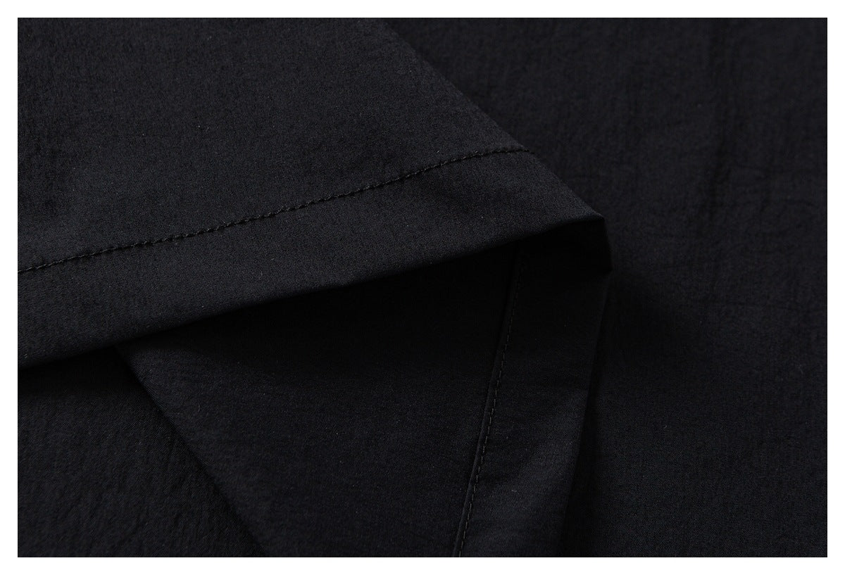 Close-up of a folded black garment edge with a stitched hem and layered fabric.