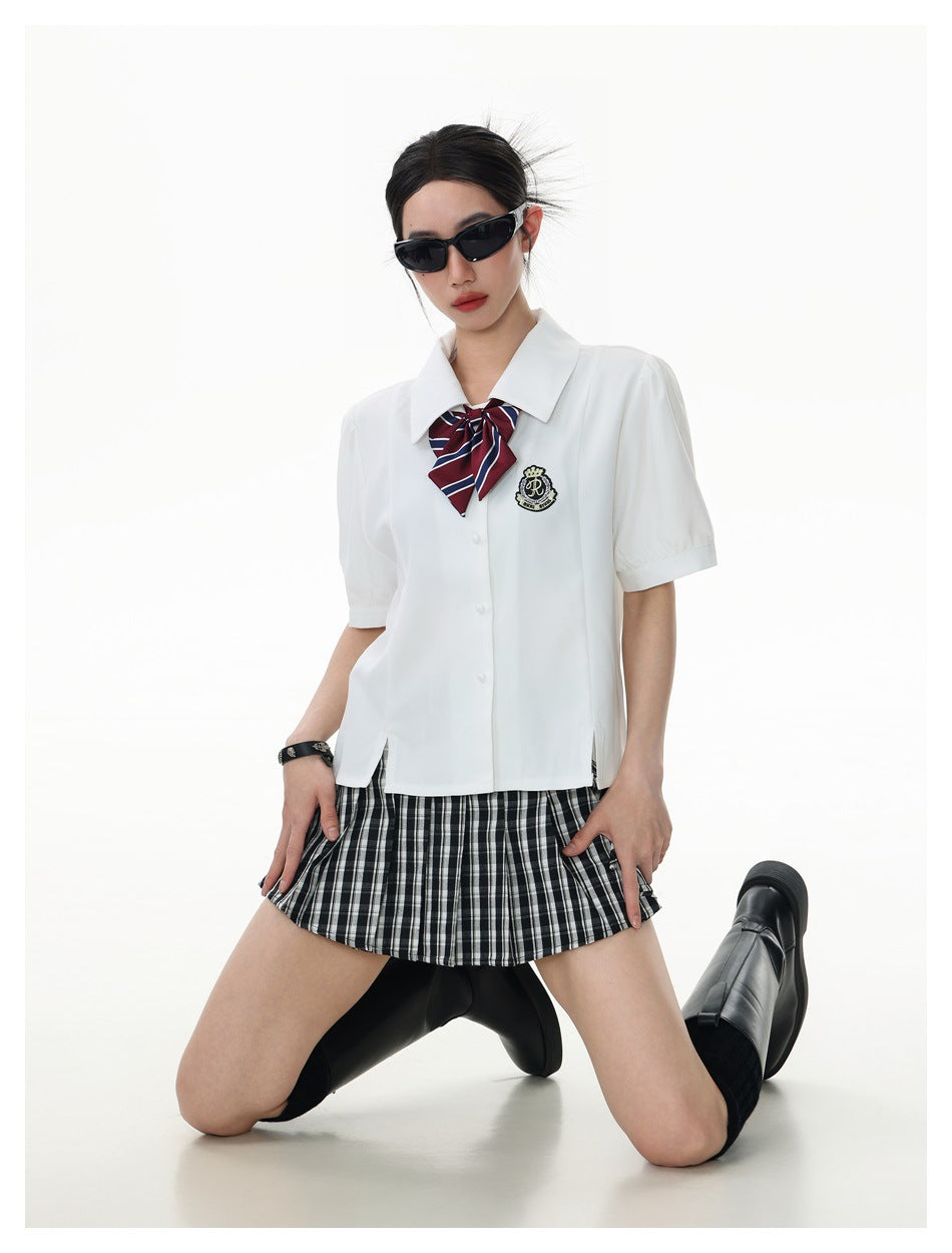 Closer view of a model wearing a white collared shirt with a striped bow and black-and-white plaid skirt.