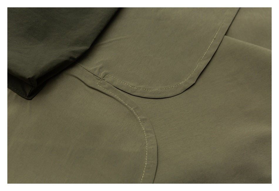 Close-up of curved stitched pocket edges on olive fabric.