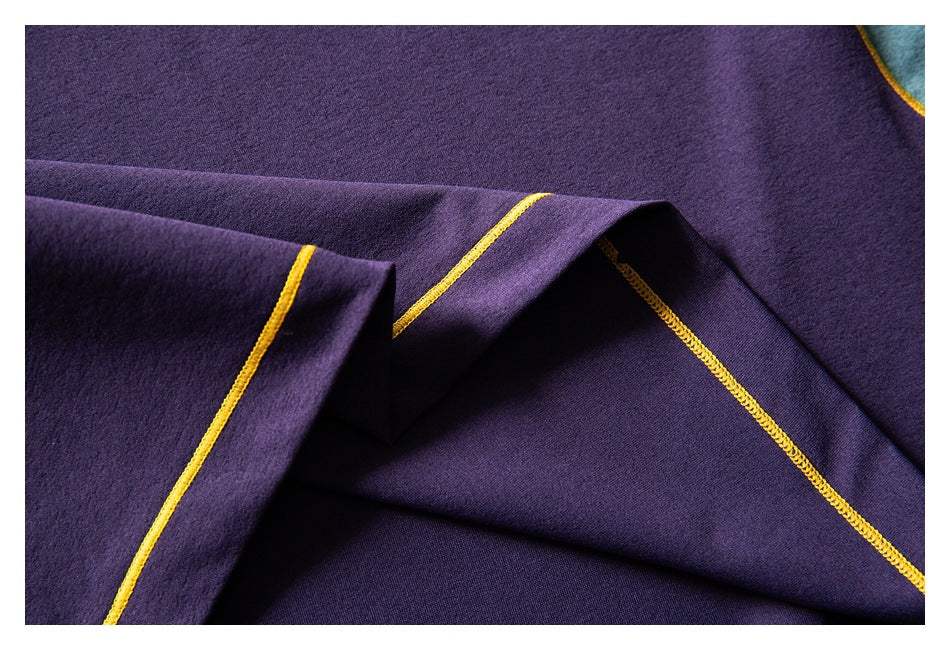 Close-up of folded purple garment fabric showing mustard-yellow overlock stitching.