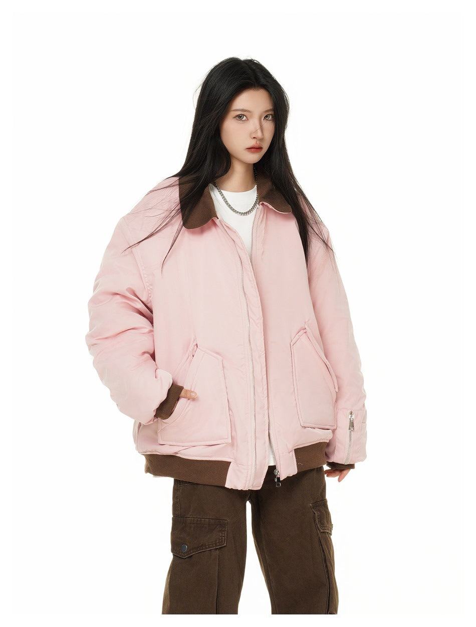 Model in a pale pink oversized zip jacket with a dark brown collar, cuffs and hem, styled with brown cargo pants.