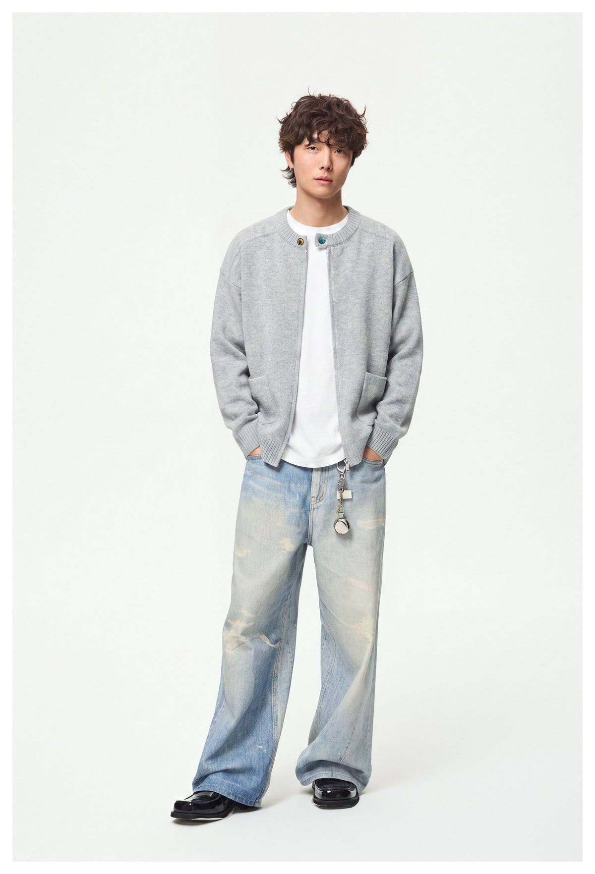 Full-length view of a model wearing a light gray zip-front cardigan with ribbed trim and patch pockets.