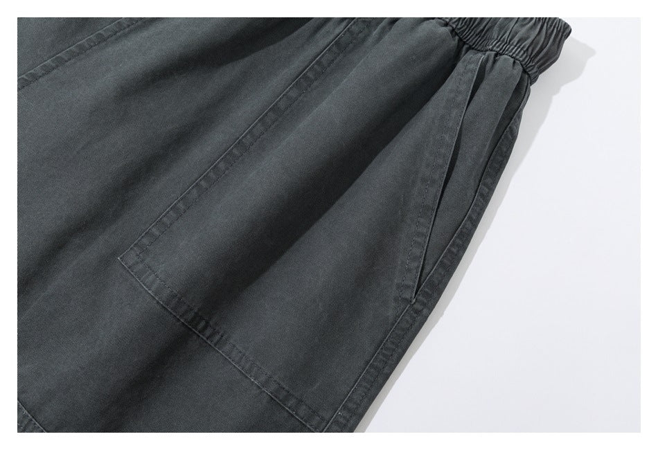 Close-up of dark charcoal pants showing a large stitched pocket and gathered elastic edge.