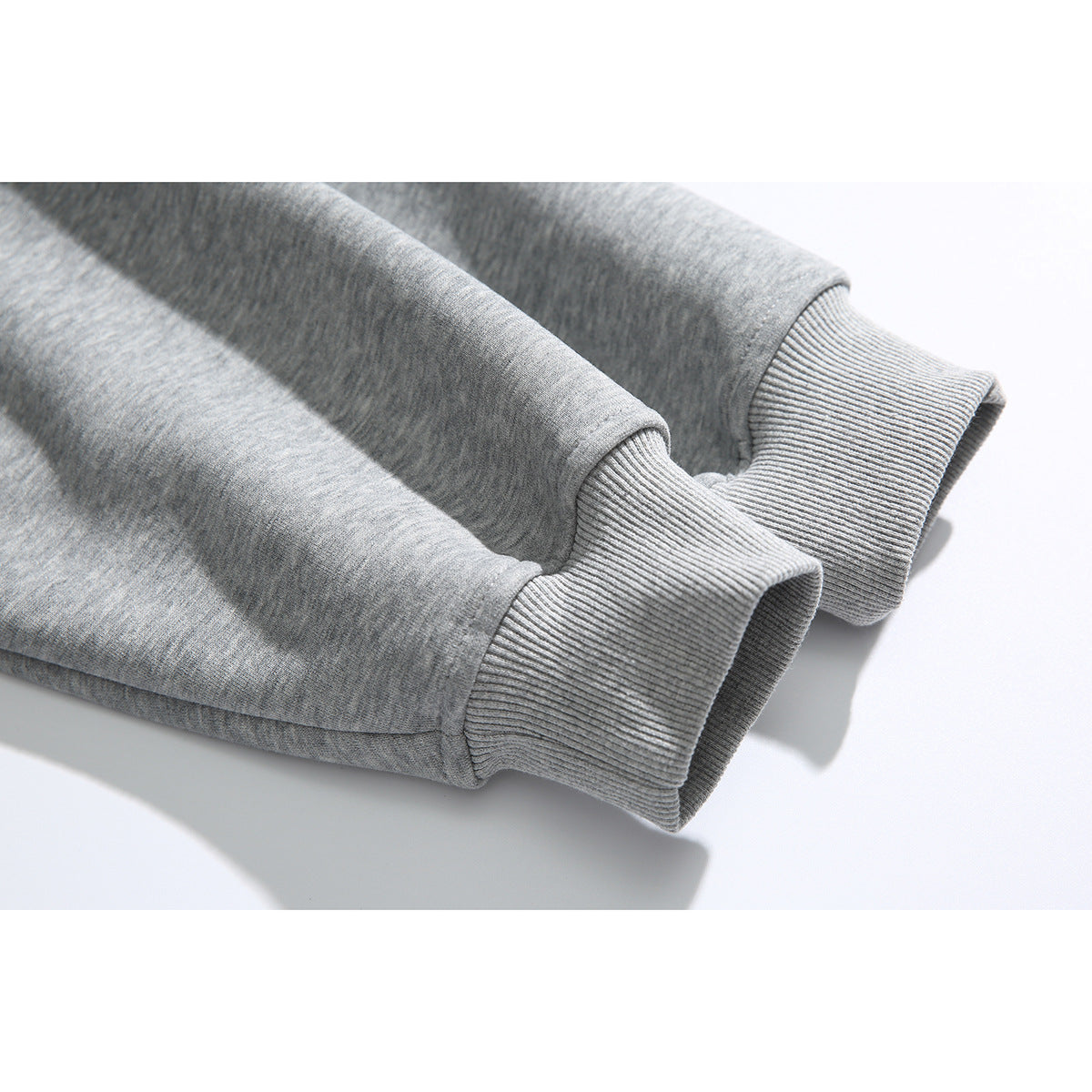 Close-up of the ribbed cuffs and sleeves of a heather gray sweatshirt.