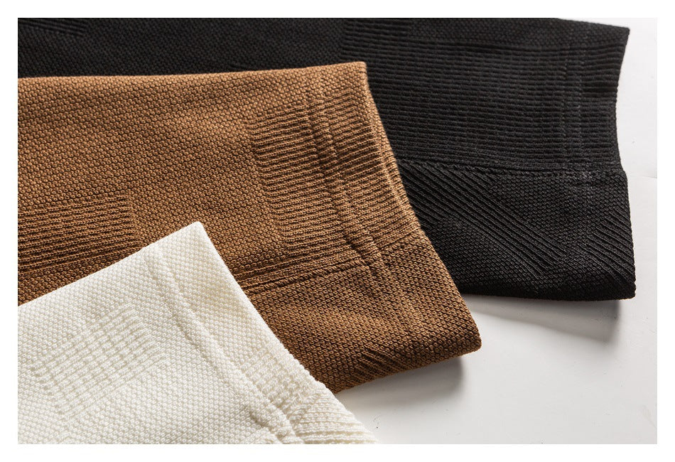 Close-up of knit garment sections in black, warm brown, and ivory, showing textured fabric and ribbed edges.