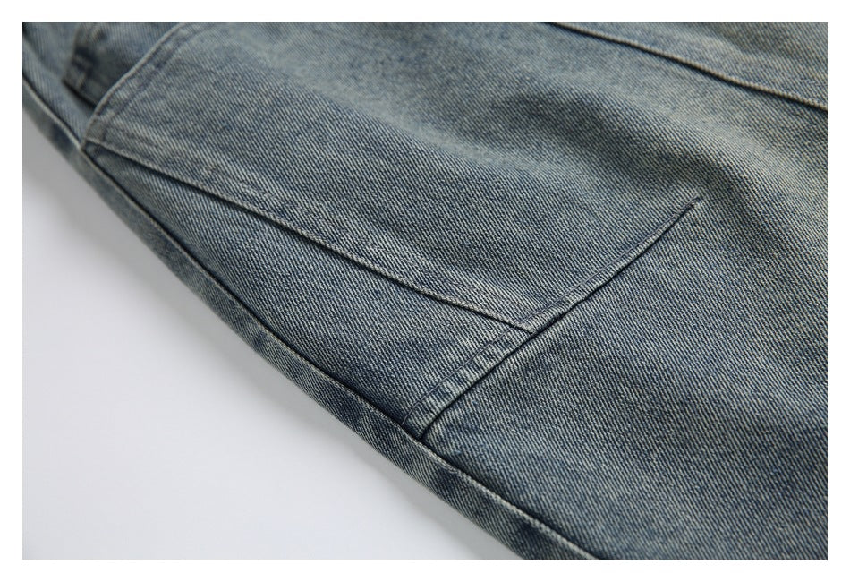 Close-up of a large stitched patch pocket on faded blue denim pants.