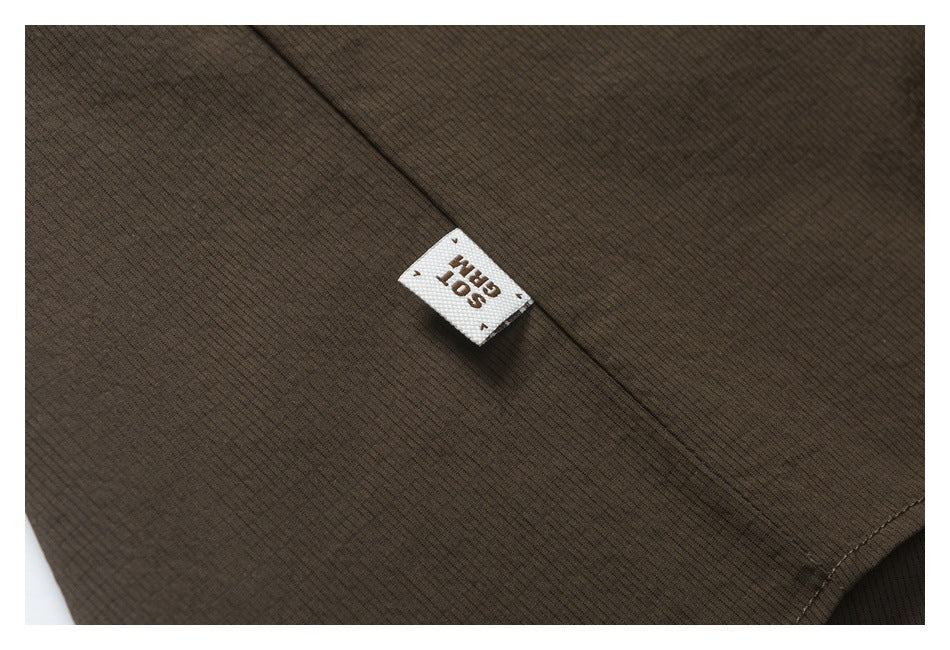 Close-up of dark brown garment fabric and seam with a small white sewn-in label.