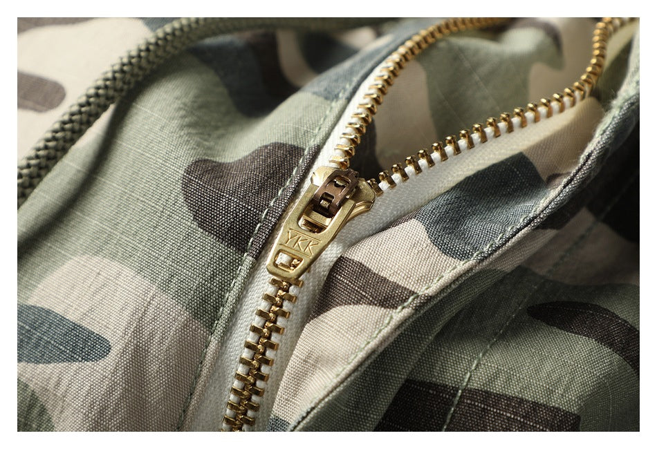 Close-up of a gold-tone zipper and drawcord on camouflage trousers.