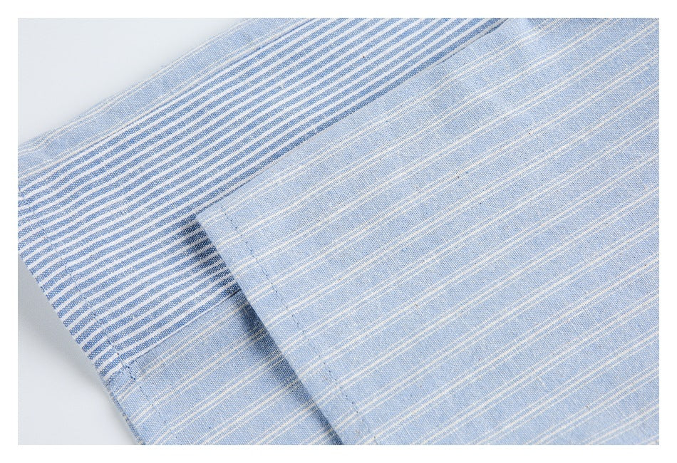 Close-up of a light blue striped garment edge with a contrasting blue-and-white striped section and stitching.