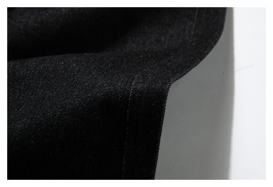 Close-up of a curved folded edge and seam on black textured fabric.