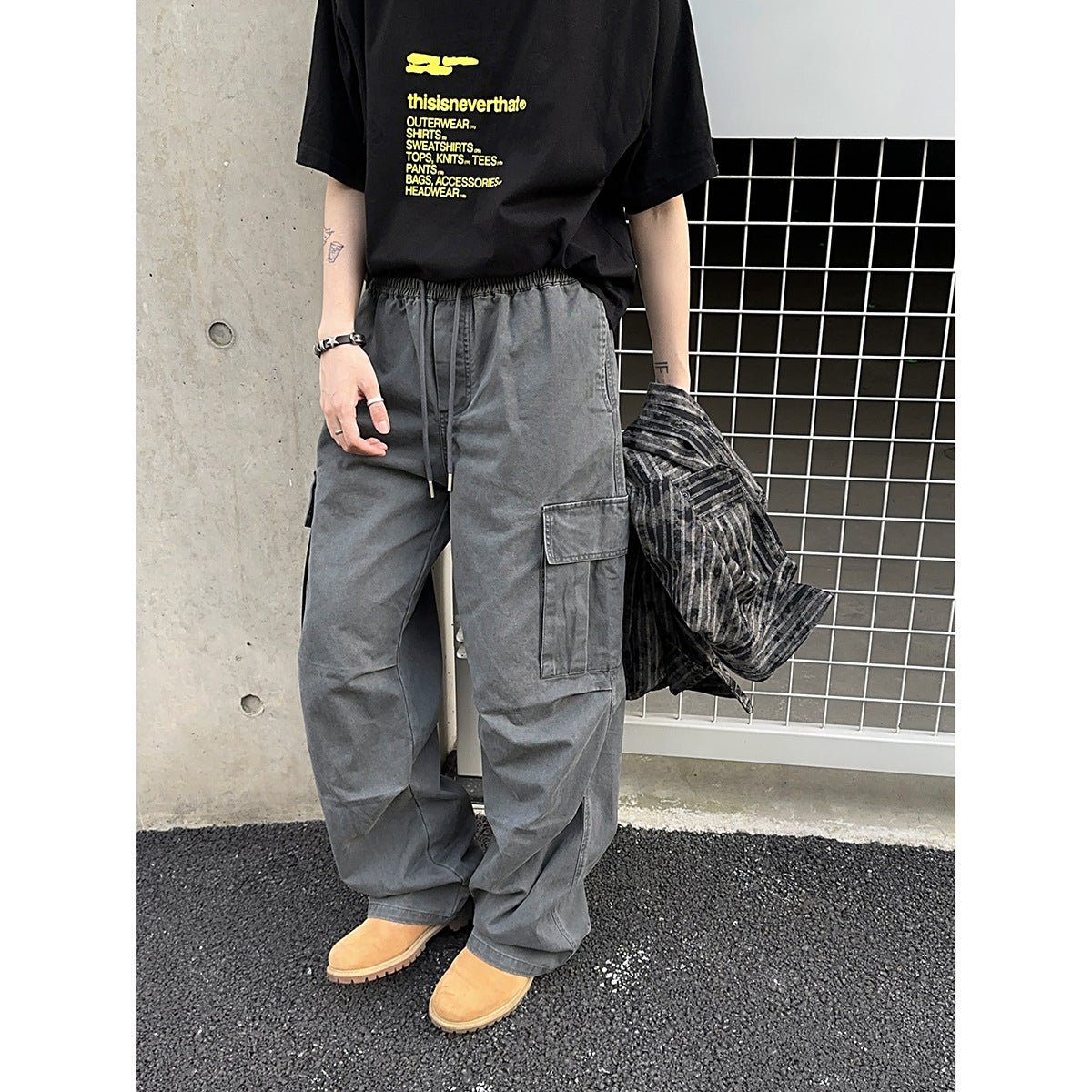 Model wearing loose gray cargo pants with an elastic drawstring waist and a large side pocket.
