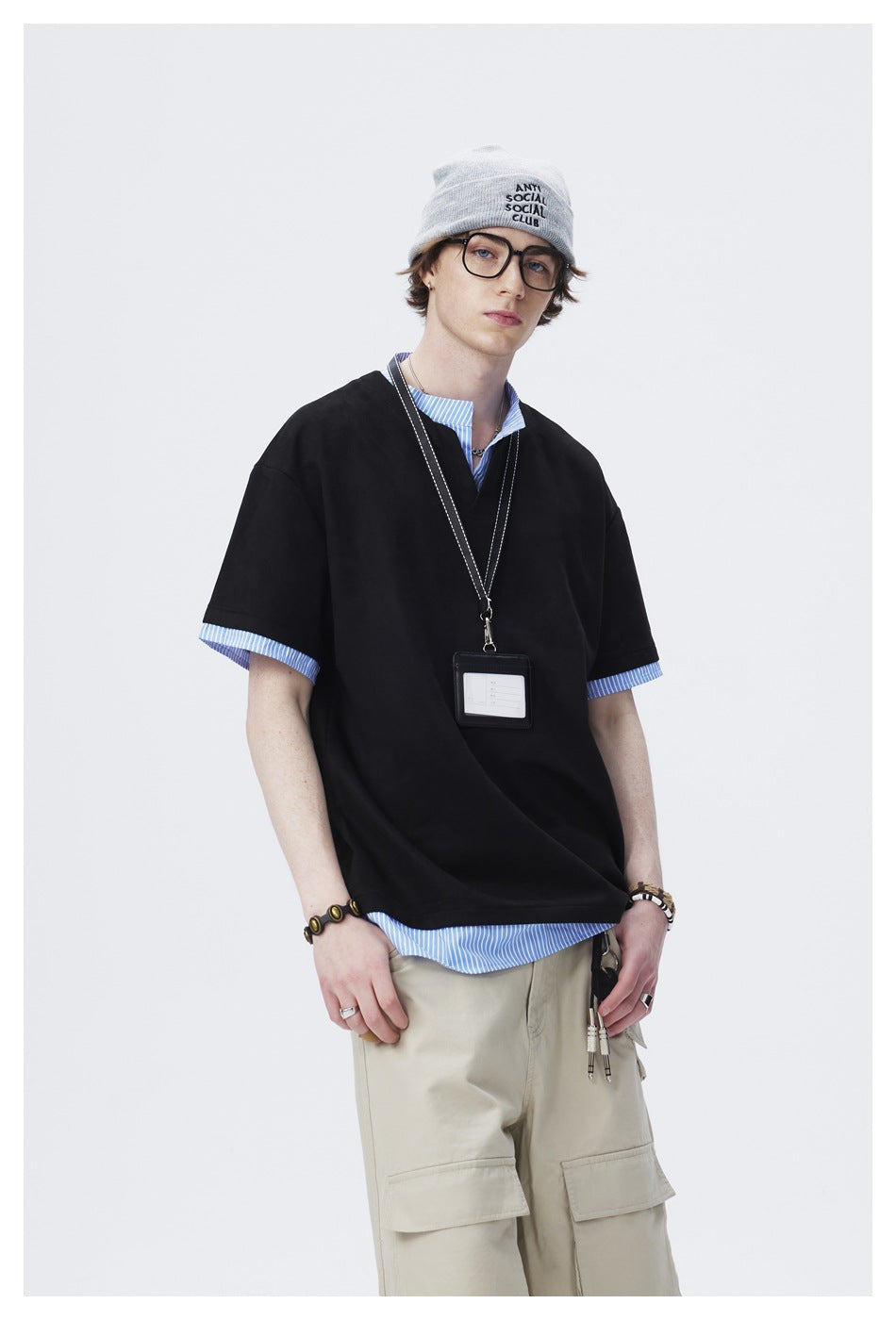Model wearing an oversized black short-sleeve top with a notched neckline and blue striped shirt details.