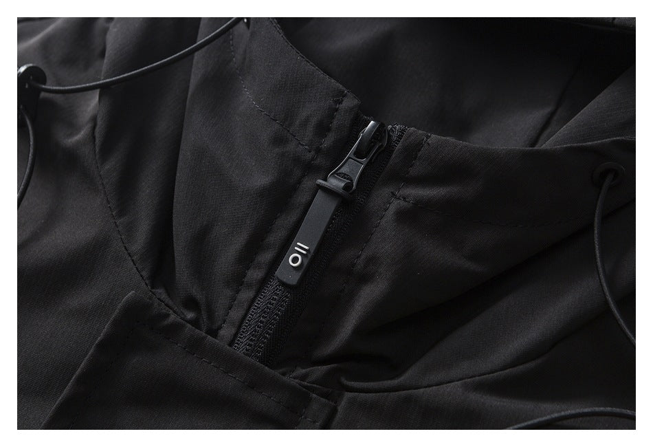 Close-up of a black jacket's front zipper, pull tab, and hood drawcords.