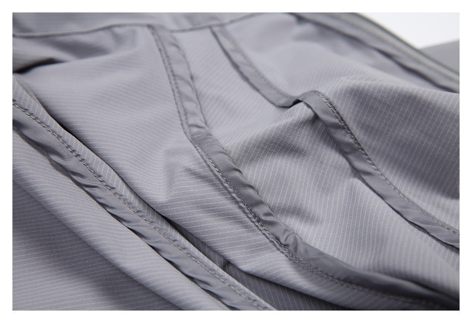 Close-up of gray striped garment seams and overlapping stitched fabric panels.
