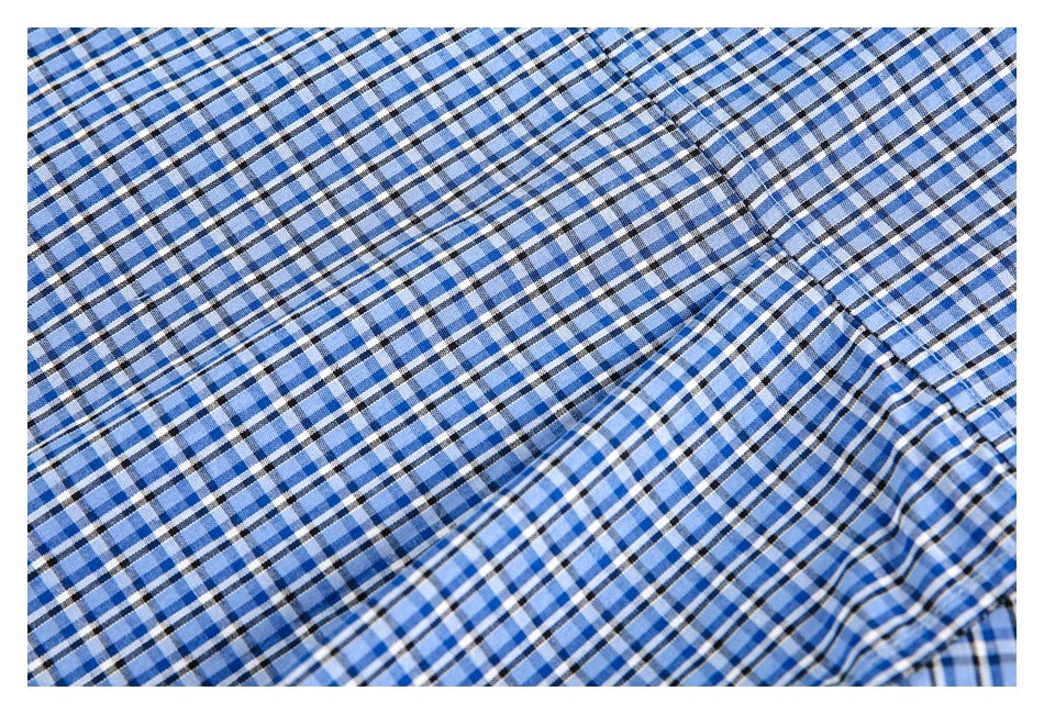 Close-up of blue, white and black plaid fabric with curved seams and folds.
