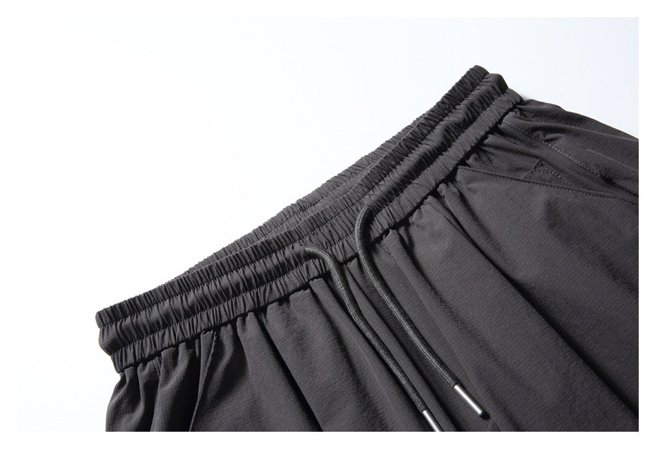 Close-up of the black pants' elastic waistband, drawstrings with metal tips and upper pocket area.