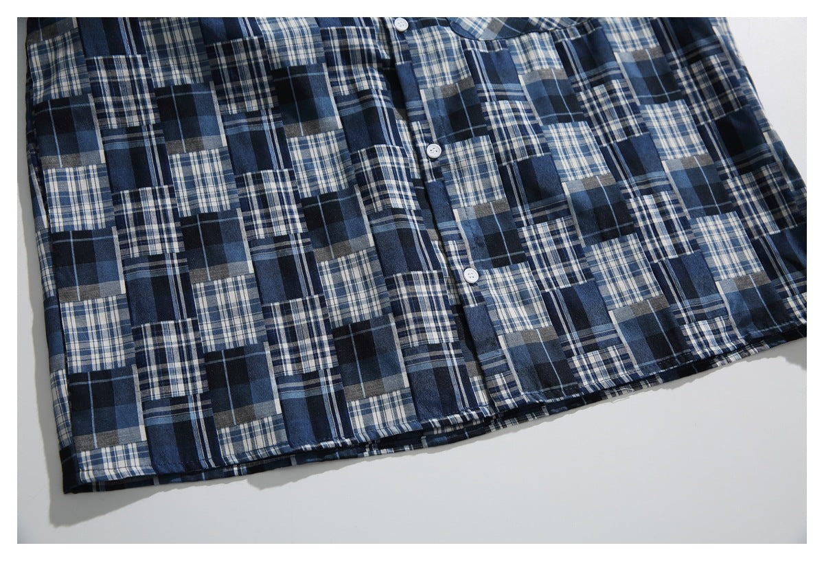 Cropped flat-lay view of the front of a navy, blue, gray, and white patchwork plaid button-up shirt.