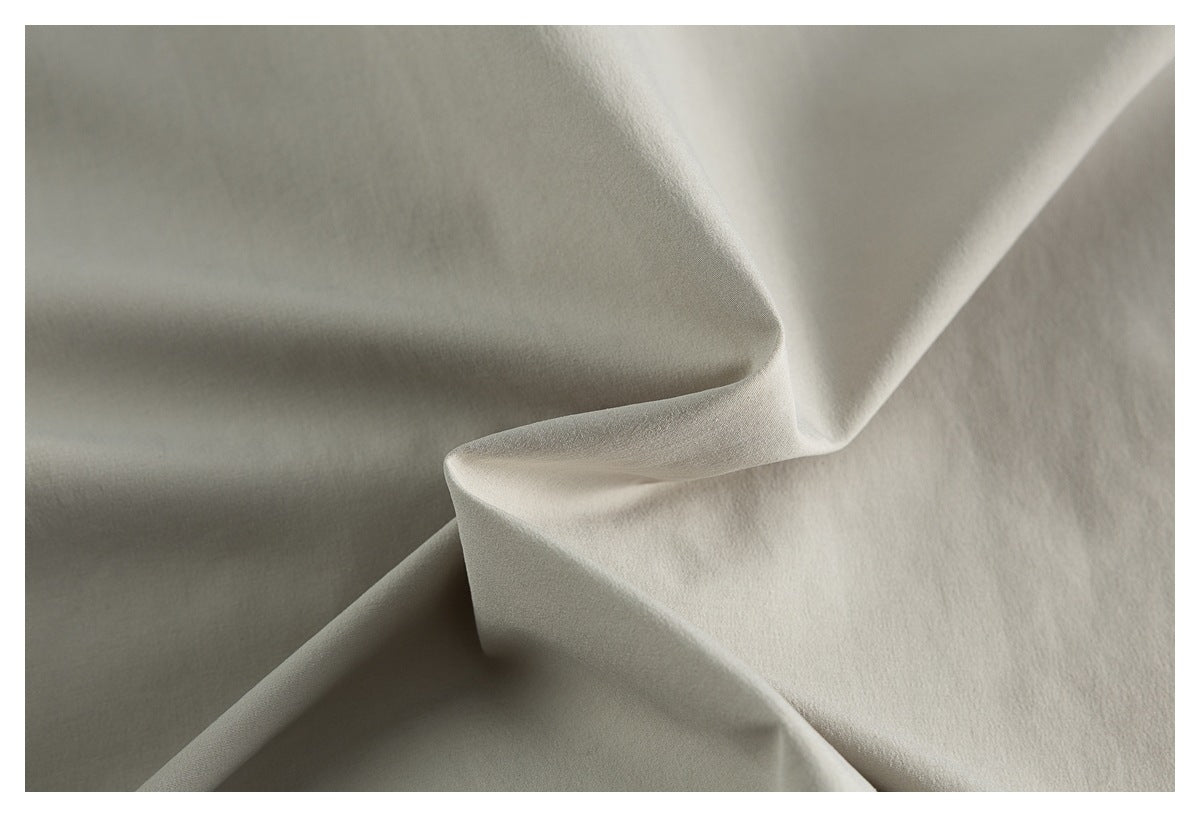 Close-up of light gray fabric arranged in soft folds, showing its smooth surface.