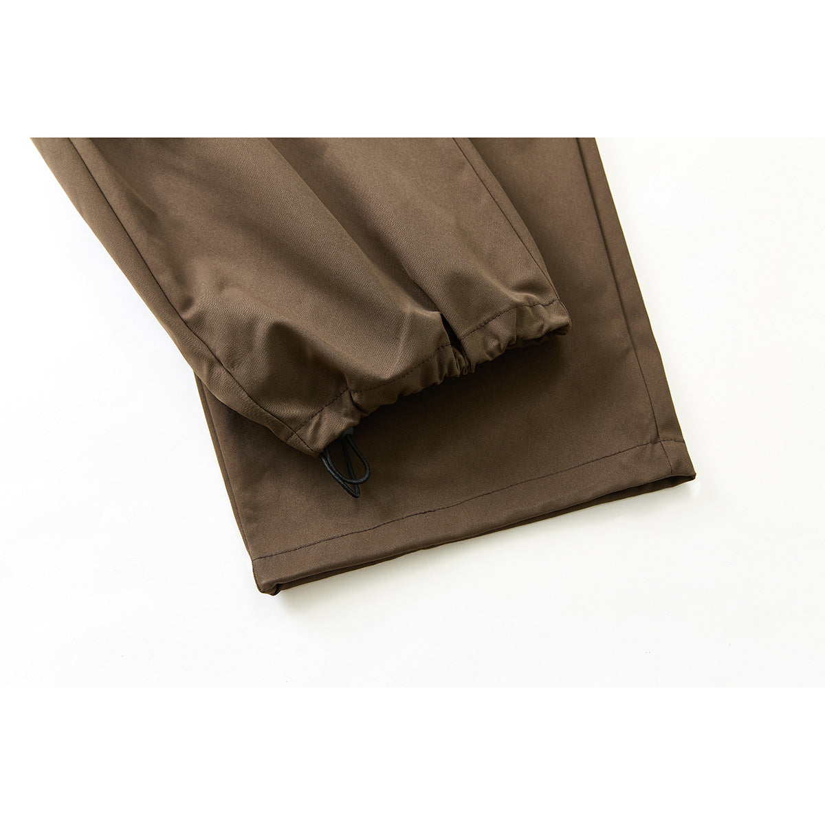 Close-up of brown pants cuffs with elasticated inner hems and a black loop detail.