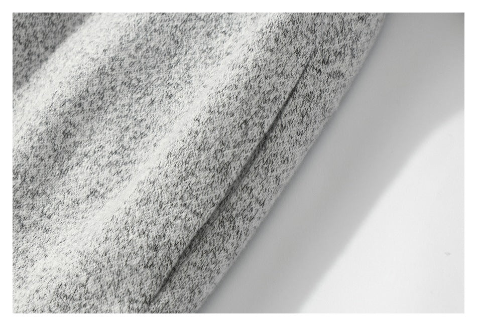 Close-up of the edge and seam of light gray marled knit fabric on a white background.