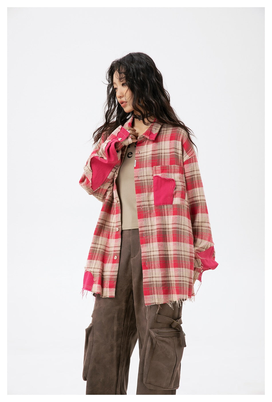 Model in oversized pink plaid shirt with hot-pink sleeve patches and frayed hem, three-quarter side view