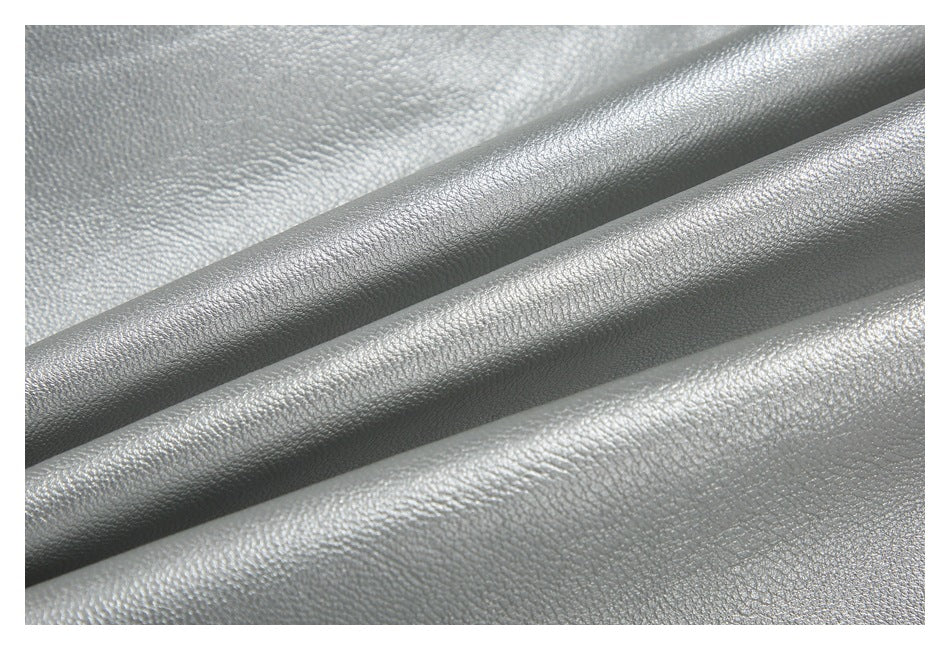 Close-up of shiny silver material arranged in soft folds, showing its pebbled surface.