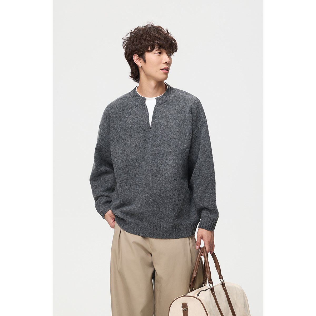 Model wearing a charcoal gray split-neck sweater with ribbed cuffs and hem, paired with beige trousers.