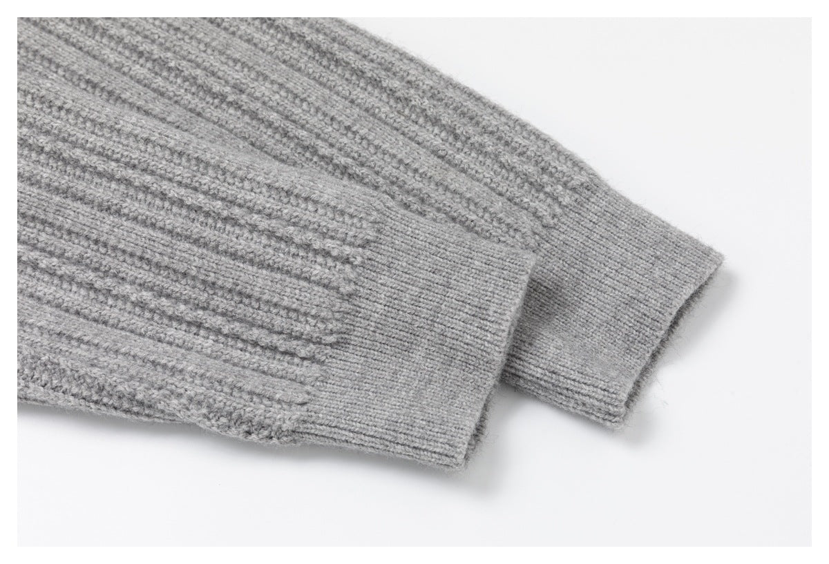 Close-up of two light gray sweater sleeves with ribbed cuffs and textured knit.