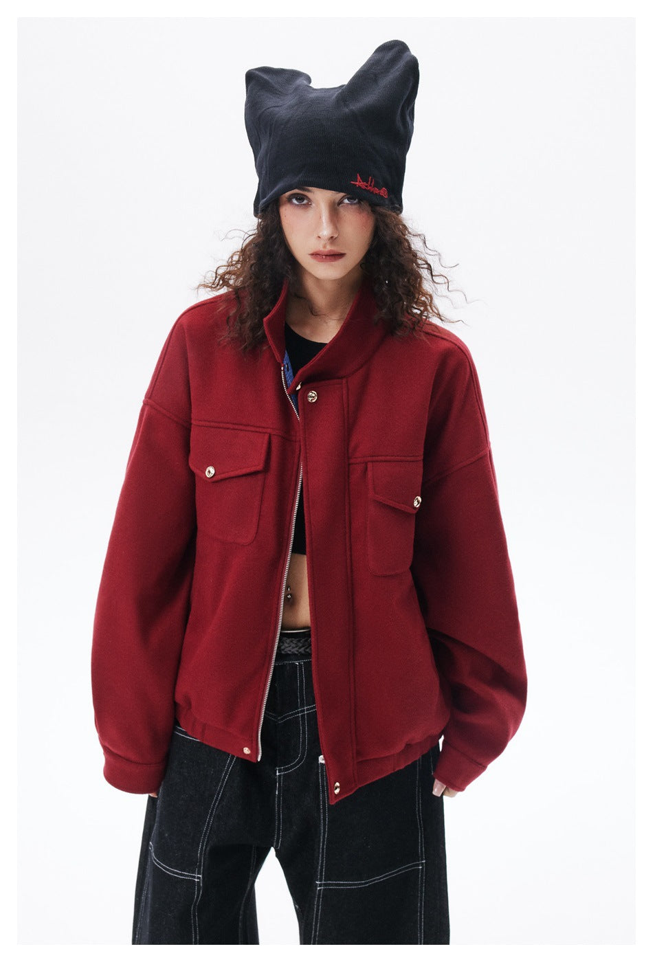 Close-up of a model wearing the red zip jacket with flap chest pockets and a dark beanie