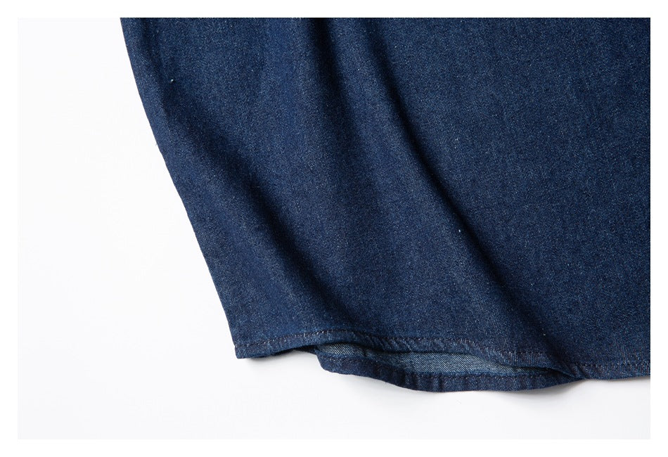 Close-up of the curved hem and stitching on a dark indigo shirt.