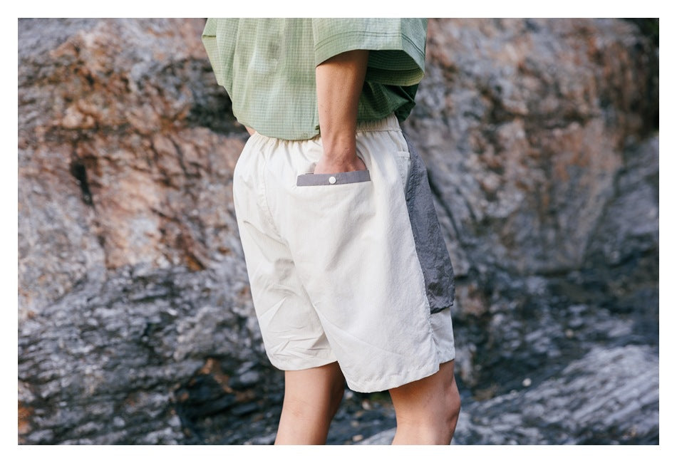 Close rear view of ivory shorts with a gray-trimmed back pocket and gray side panel.