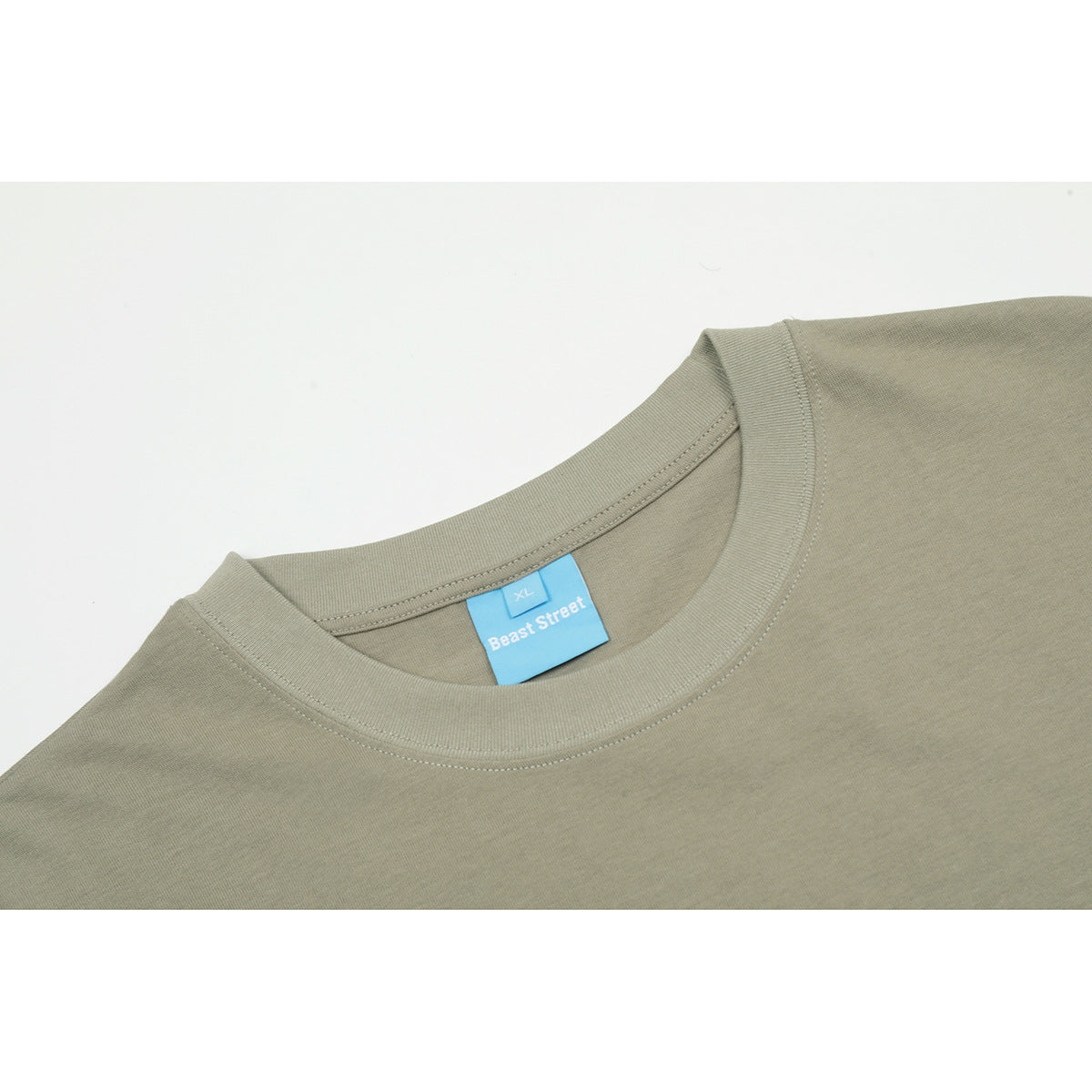 Close-up of an olive-gray T-shirt crew neck with a blue Beast Street XL label.