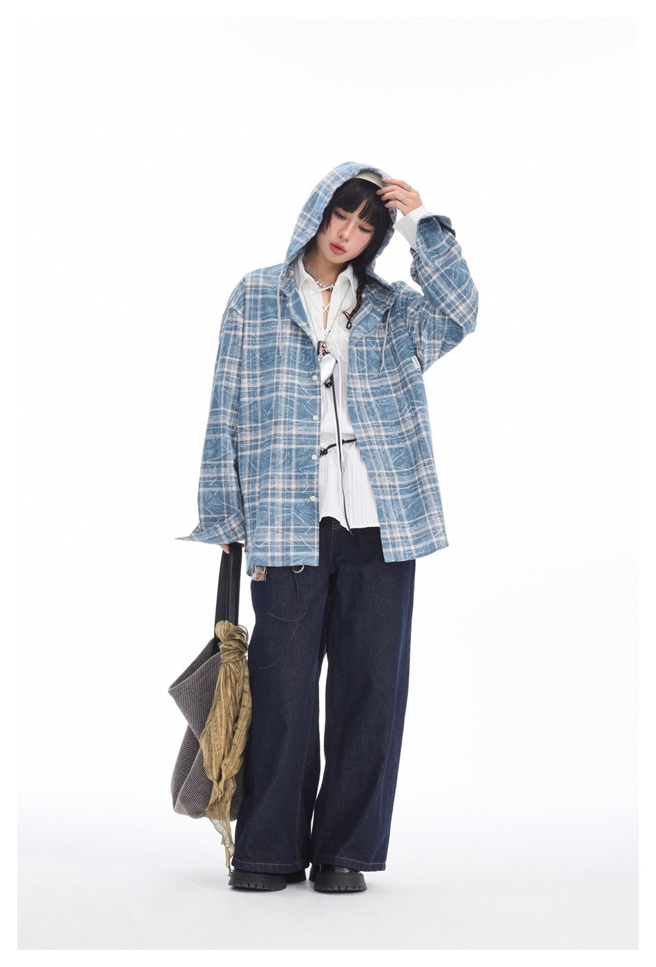 Full-length studio view of a model wearing a blue-and-white plaid hooded jacket, white blouse, and dark wide-leg jeans.